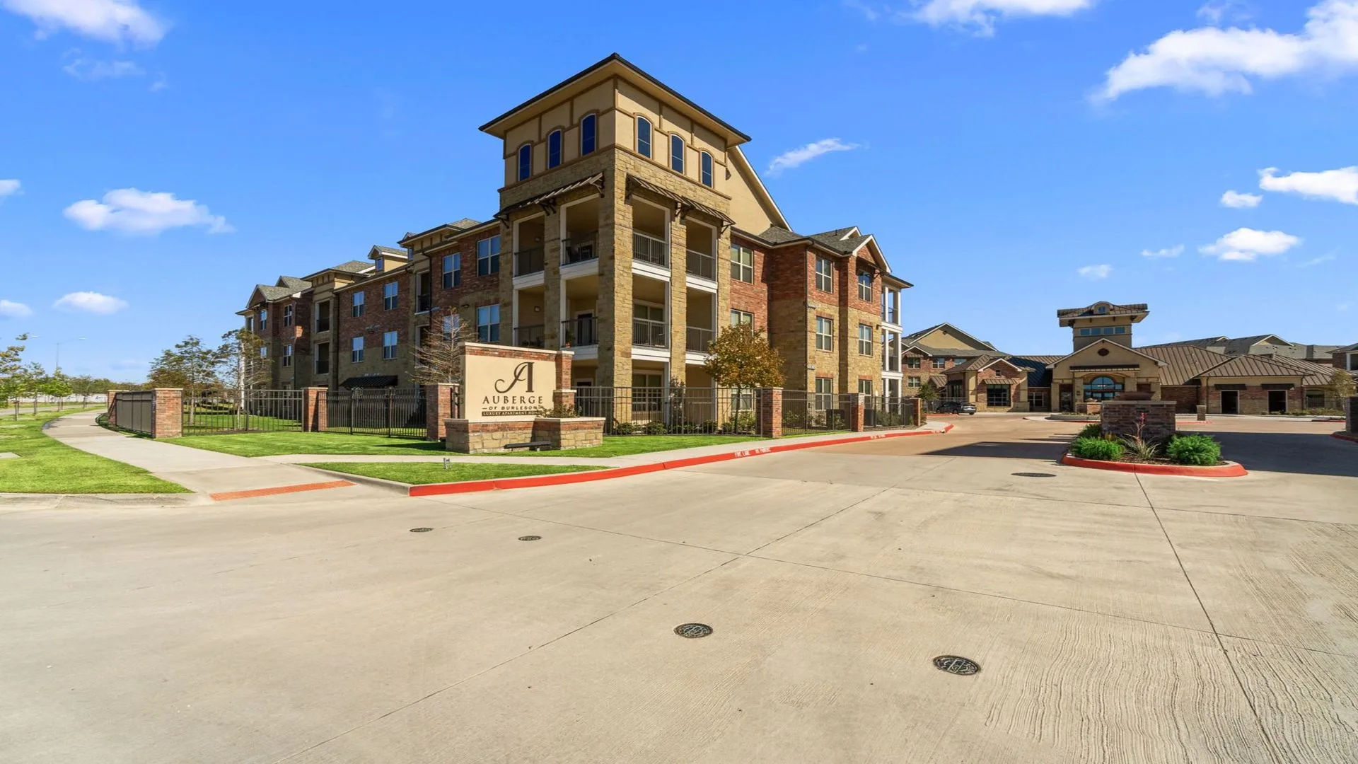 the front entrance to a large apartment complex at The Auberge of Burleson