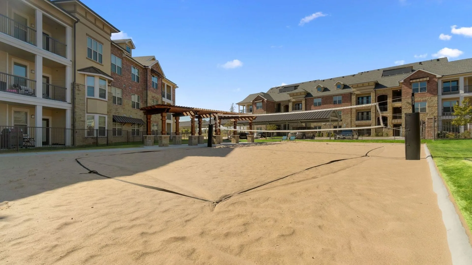 a volleyball court in front of apartment buildings at The Auberge of Burleson