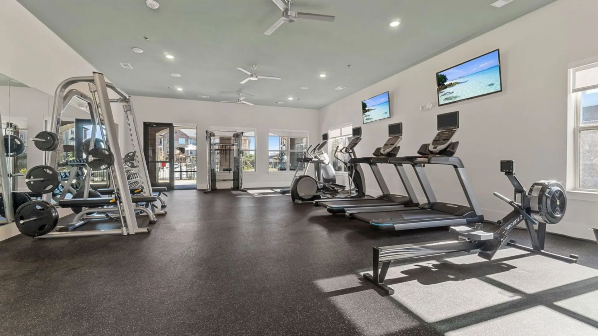 a gym room with treadmills, weights and televisions at The Auberge of Burleson